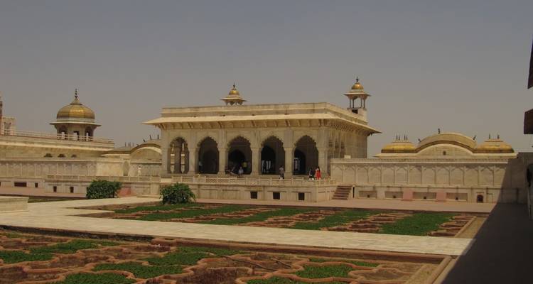 Terrace garden with Mughal architecture in the background and a few visitors.