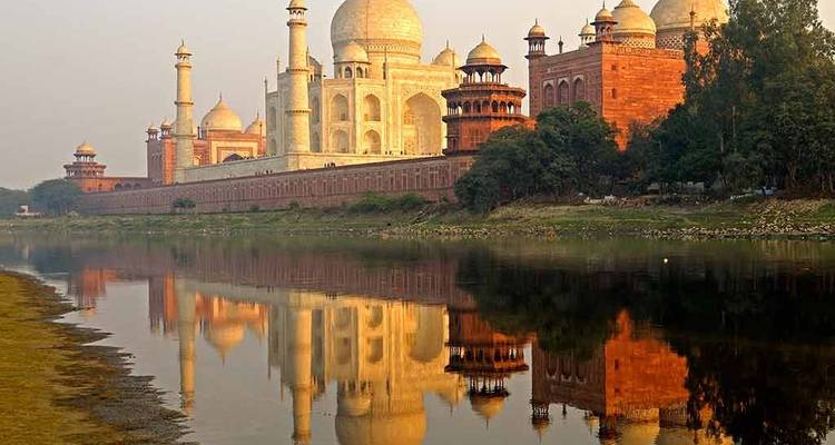 Reflectie van de Taj Mahal in een rivier bij zonsopgang.