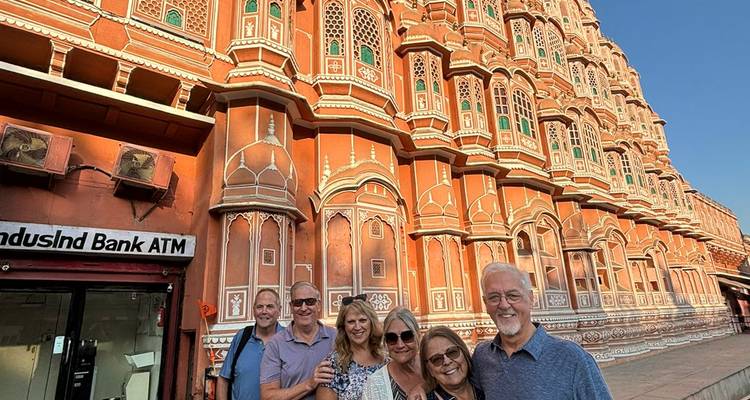 Los visitantes posan frente a la ornamentada fachada de celosía rosa del Hawa Mahal de Jaipur bajo la cálida luz de la tarde.