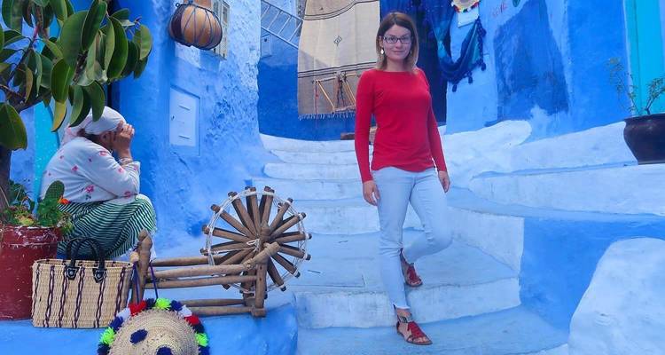 Two women in a blue-painted alley with traditional elements, one seated and another standing.