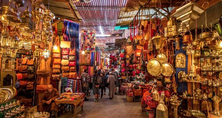 Callejón bullicioso del mercado con productos coloridos y lámparas.