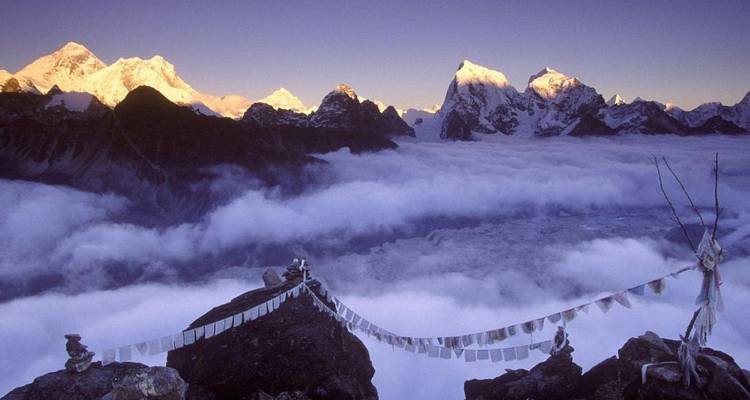 Impresionante paisaje montañoso con nubes y banderas de oración.