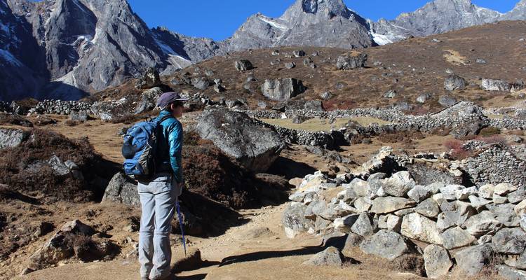 Persona caminando por un paisaje rocoso con picos altos.