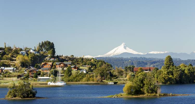Scenic view of a lake with houses and mountains in the background.
