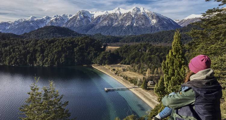 Person looking out over a lake with snow-capped mountains in the distance.
