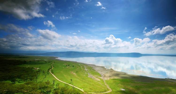 Scenic view of a vast lake with grasslands and blue sky.