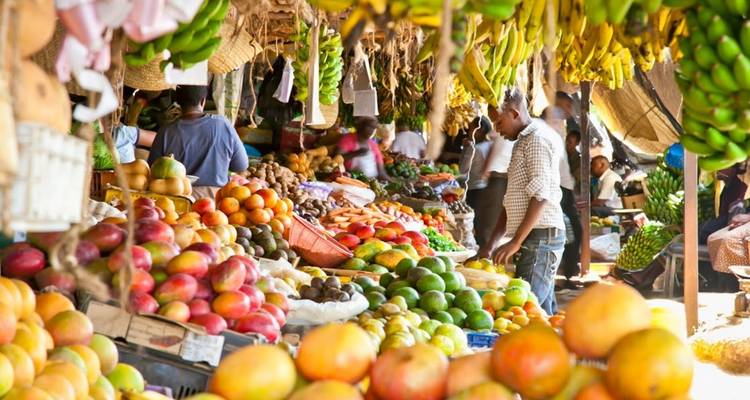Drukke marktscène met verschillende vruchten en groenten.