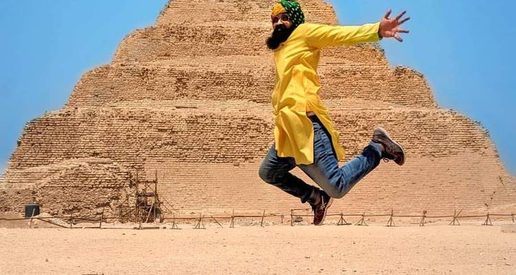 Persoon die speels springt voor een oude stenen piramide.