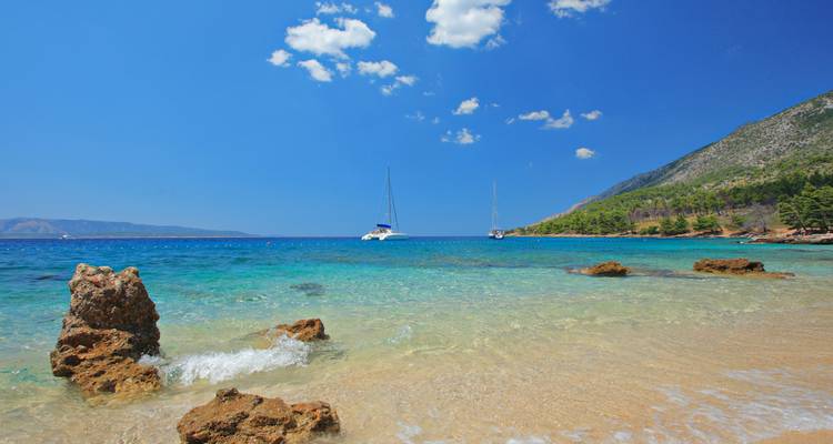 Playa prístina con aguas azules cristalinas y veleros.