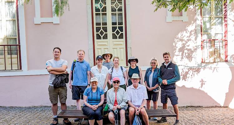 Portrait de groupe de voyageurs posant devant un bâtiment rose pastel.