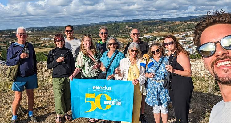 Photo de célébration en plein air de voyageurs tenant une banderole anniversaire sur le sommet d'une colline.