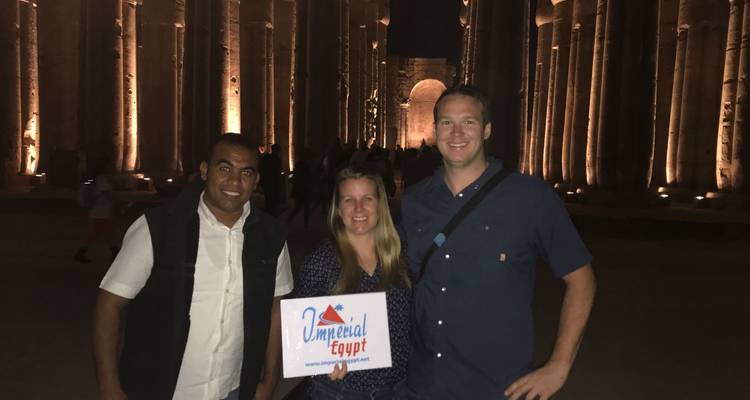 Group holding a sign in front of a lit-up temple at night.
