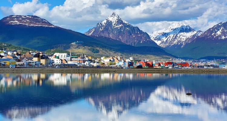 Des montagnes enneigées se reflétant dans un plan d'eau calme.