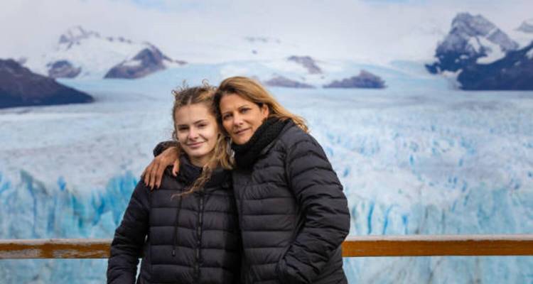 Twee vrouwen poseren met besneeuwde bergen op de achtergrond.