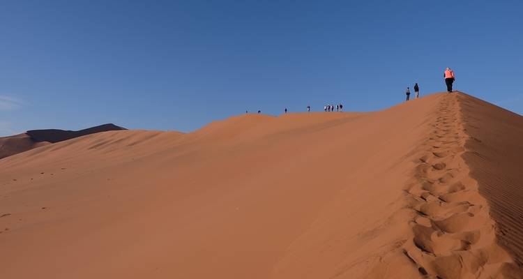 Un groupe de personnes marchant sur le sommet d'une dune de sable.