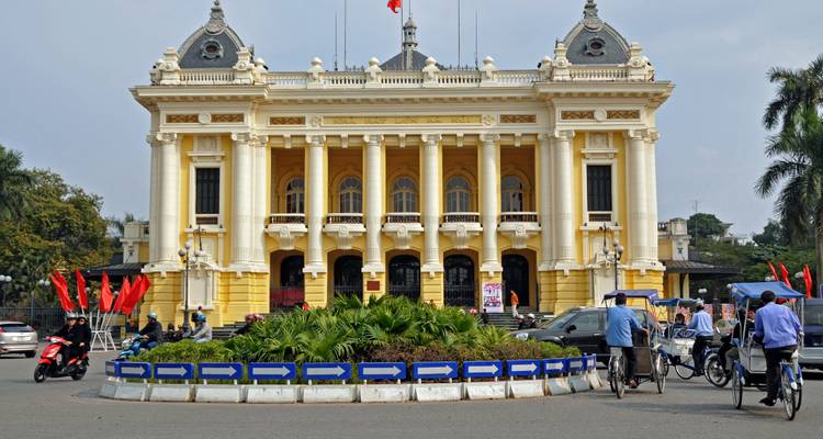 Großes historisches Gebäude mit Menschen und Fahrrädern davor.