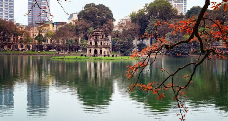 Malerischer Seeblick mit einem alten Turm und Herbstlaub.
