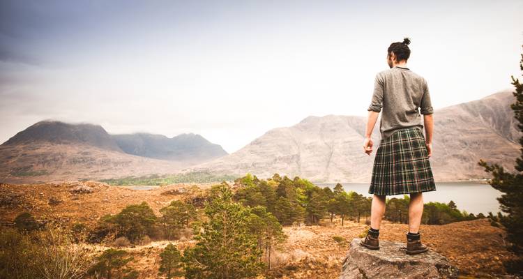 Homme en kilt contemplant un paysage montagneux pittoresque.