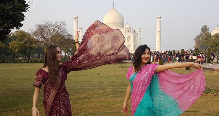 Zwei Frauen posieren fröhlich vor dem Taj Mahal.