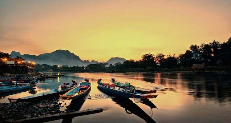 Zonsondergangscène met langboten op een serene rivier.