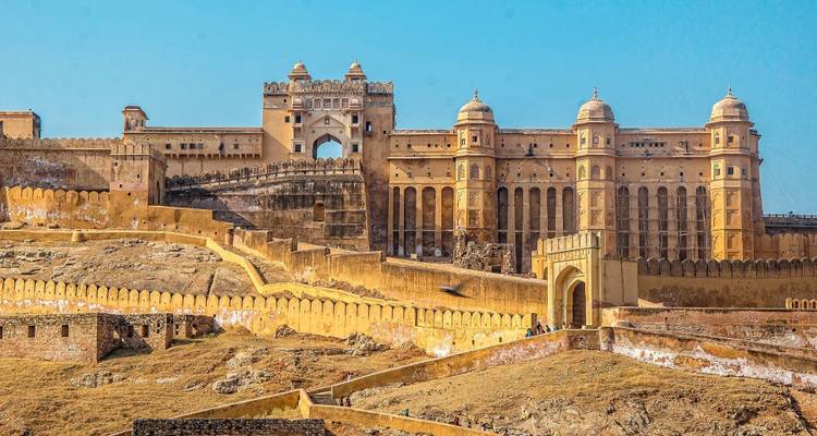 Expansive Amber Fort complex perched on arid hills with fortified walls under clear sky.