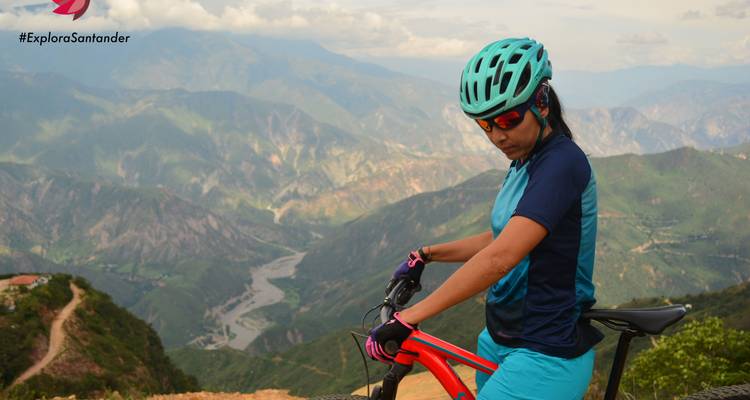 Un ciclista contemplando un valle con montañas distantes.