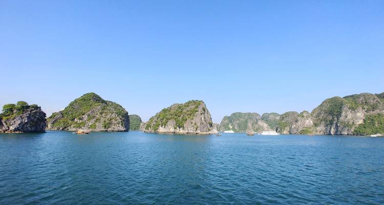 Zicht op kalkstenen karstformaties die oprijzen uit het blauwe water van Halong Bay.