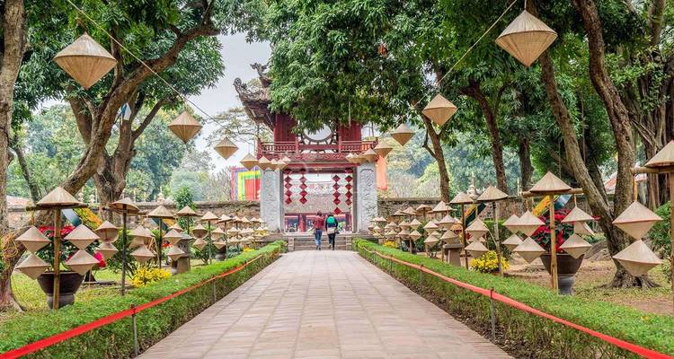 Ingangspad omzoomd met traditionele Vietnamese hoeden dat naar een historisch gebouw leidt.