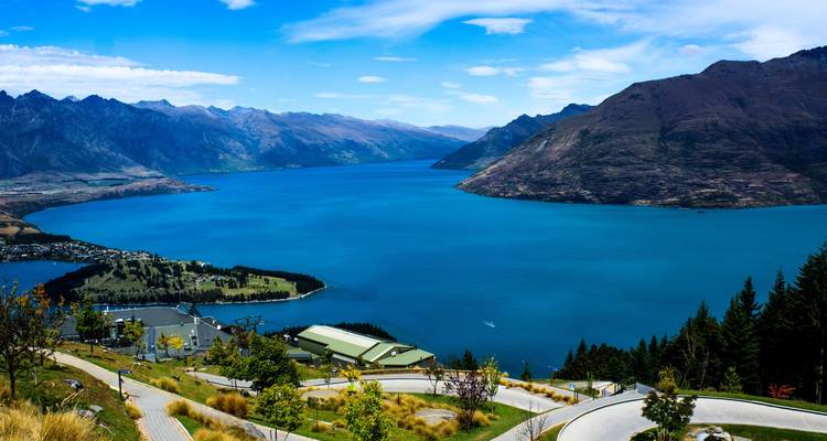 Panoramic view over Queenstown and deep-blue Lake Wakatipu framed by mountain ranges.