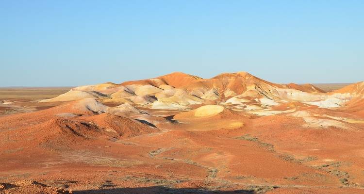 Colinas erosionadas coloridas bajo un cielo azul despejado.