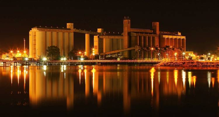 Una instalación industrial brillantemente iluminada reflejada en las aguas nocturnas.