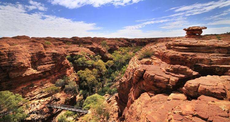 Weitläufiger Blick auf eine Schlucht mit Grünflächen und einer Brücke.