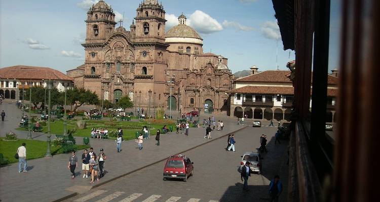 Lively plaza in front of the historic stone cathedral in Cusco surrounded by mountains and colonial buildings.