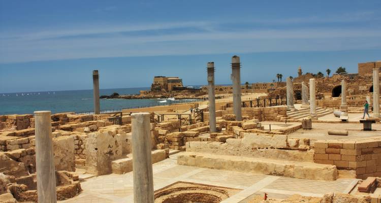 Archaeological coastal ruins of Caesarea with stone columns and the Mediterranean Sea backdrop.