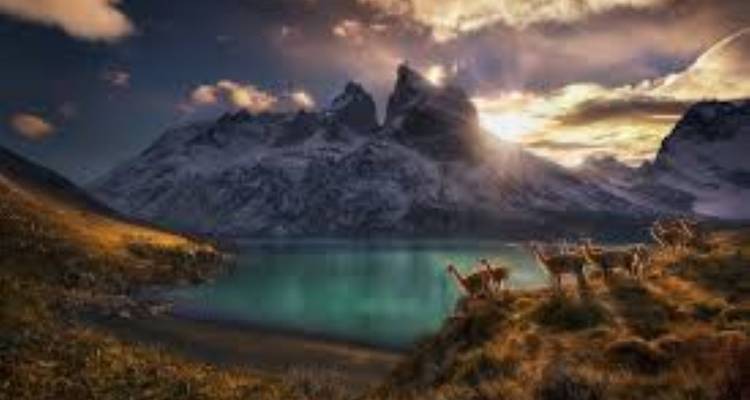 Besneeuwde bergen met een meer tijdens zonsondergang.