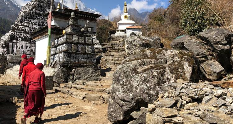 Monjes caminando junto a piedras de oración y estupas en el Himalaya.