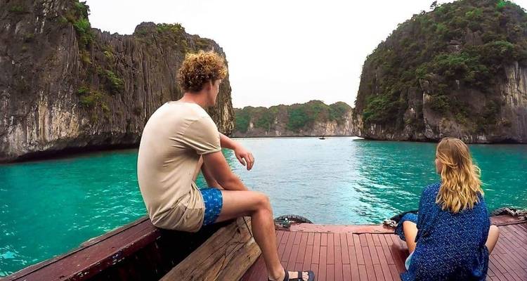 Dos personas en un barco disfrutando de la vista serena de una bahía.