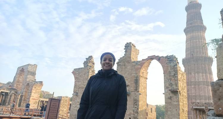 Una persona posando con ruinas históricas de fondo.