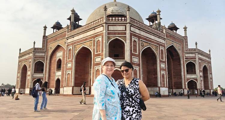 Two women standing outside Humayun’s Tomb, the red-and-white Mughal mausoleum in Delhi.