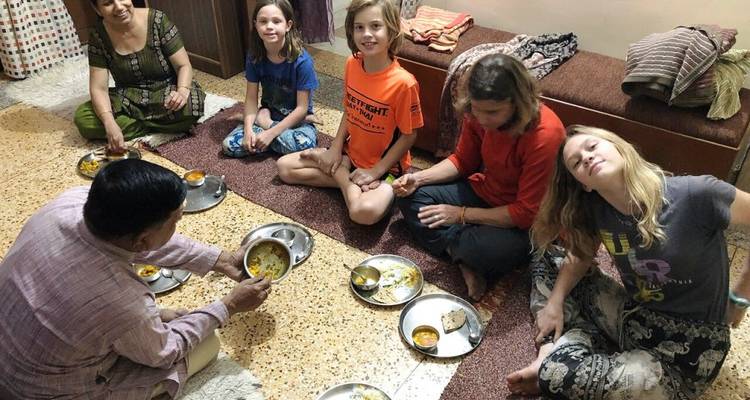 Familia sentada en el suelo compartiendo una comida.