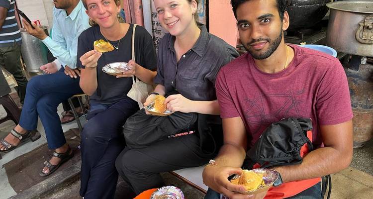 People eating local snacks while seated at a street food stall.
