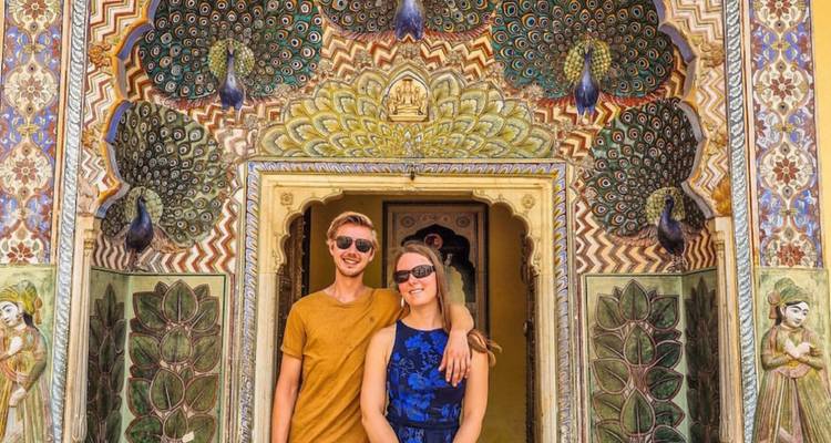 Pareja posando frente a una puerta con temática de pavo real