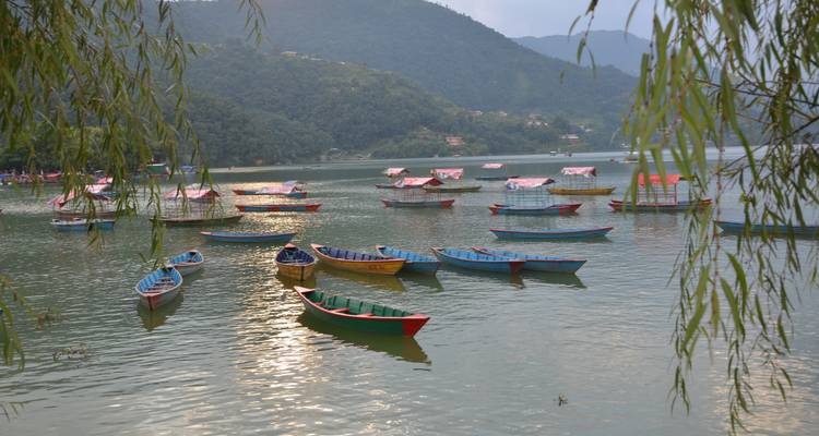 Bunte Boote auf einem friedlichen See, umgeben von grünen Hügeln.