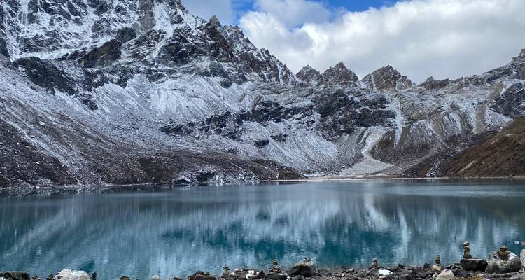 Ein ruhiger Bergsee mit Spiegelungen schneebedeckter Gipfel.