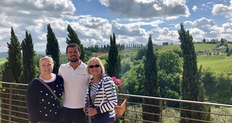 Group of tourists posing in front of vineyards under a cloudy sky.