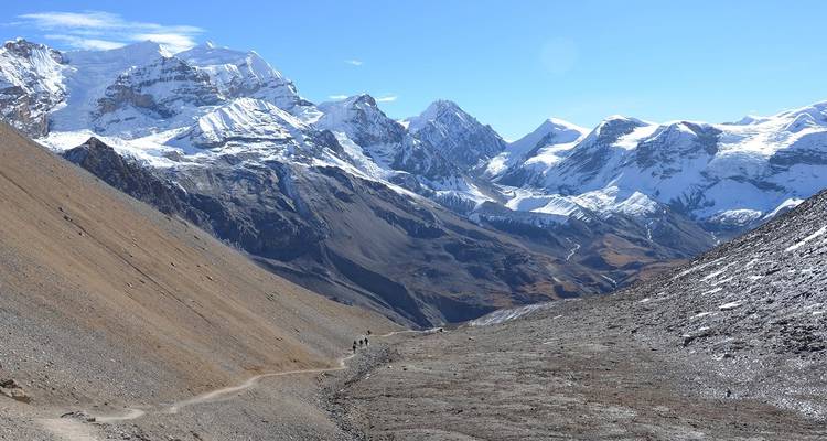 Vast mountain range with a person hiking along a trail.