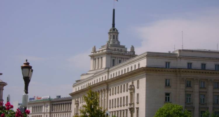 Un edificio gubernamental austero con una aguja y cielo nublado.