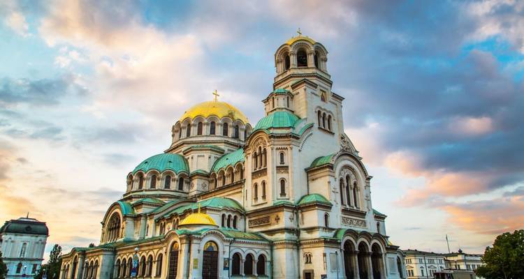 Una iglesia ornamentada con cúpulas verdes durante el atardecer.