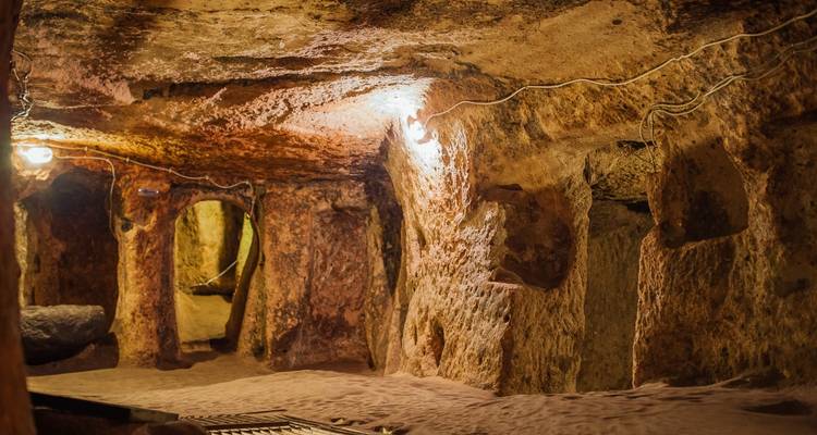 Cueva subterránea con paredes de piedra e iluminación en Capadocia.