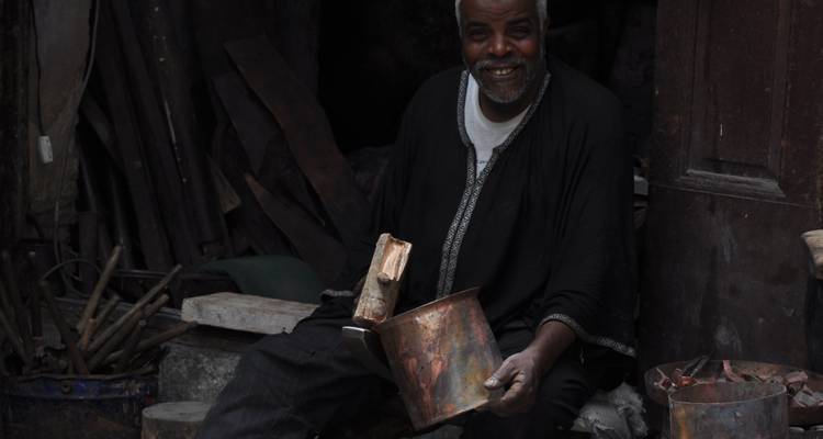 Lächelnder Mann mit einem Metalltopf in einer Werkstatt